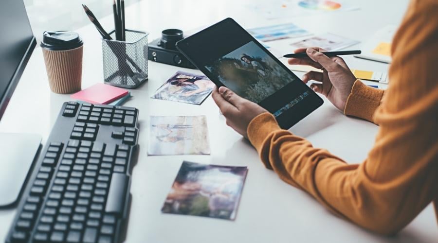 Someone editing an image on a tablet, with a keyboard and desk in the background