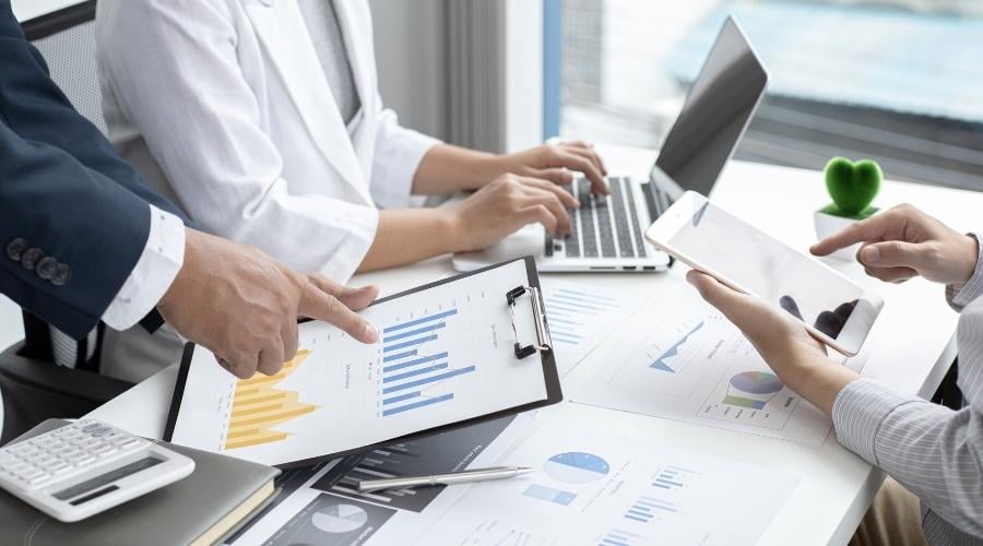 Group of people looking at graphs, computers and tablets